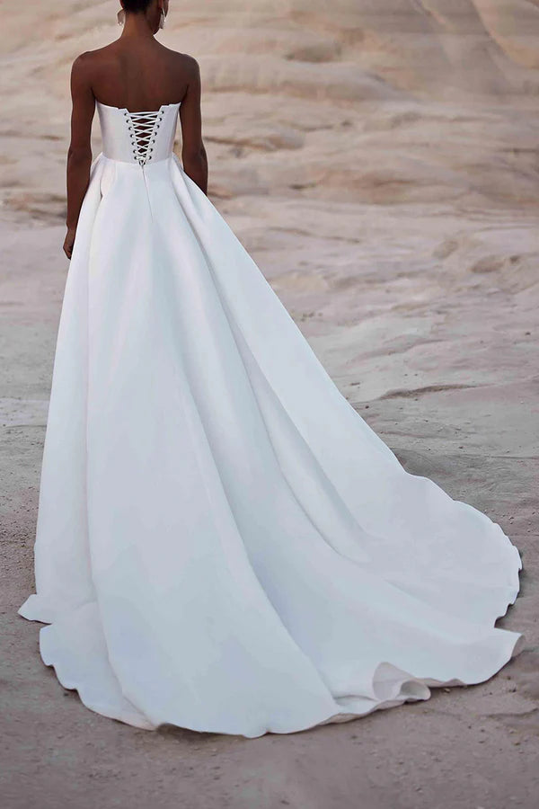 Un abito da sposa in raso bianco con strascico a palazzo e senza spalline